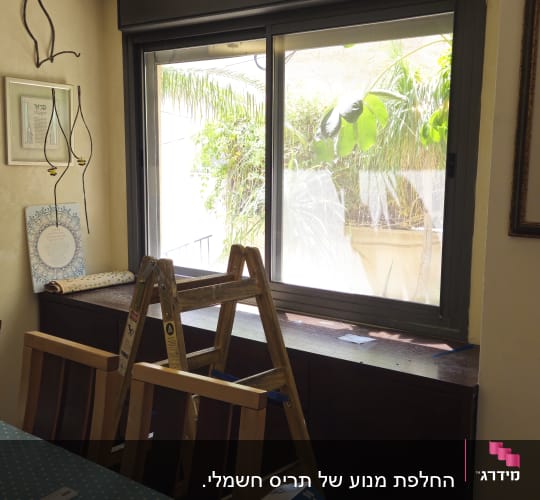 חלון עם תריסים וסולם בחדר פנימי